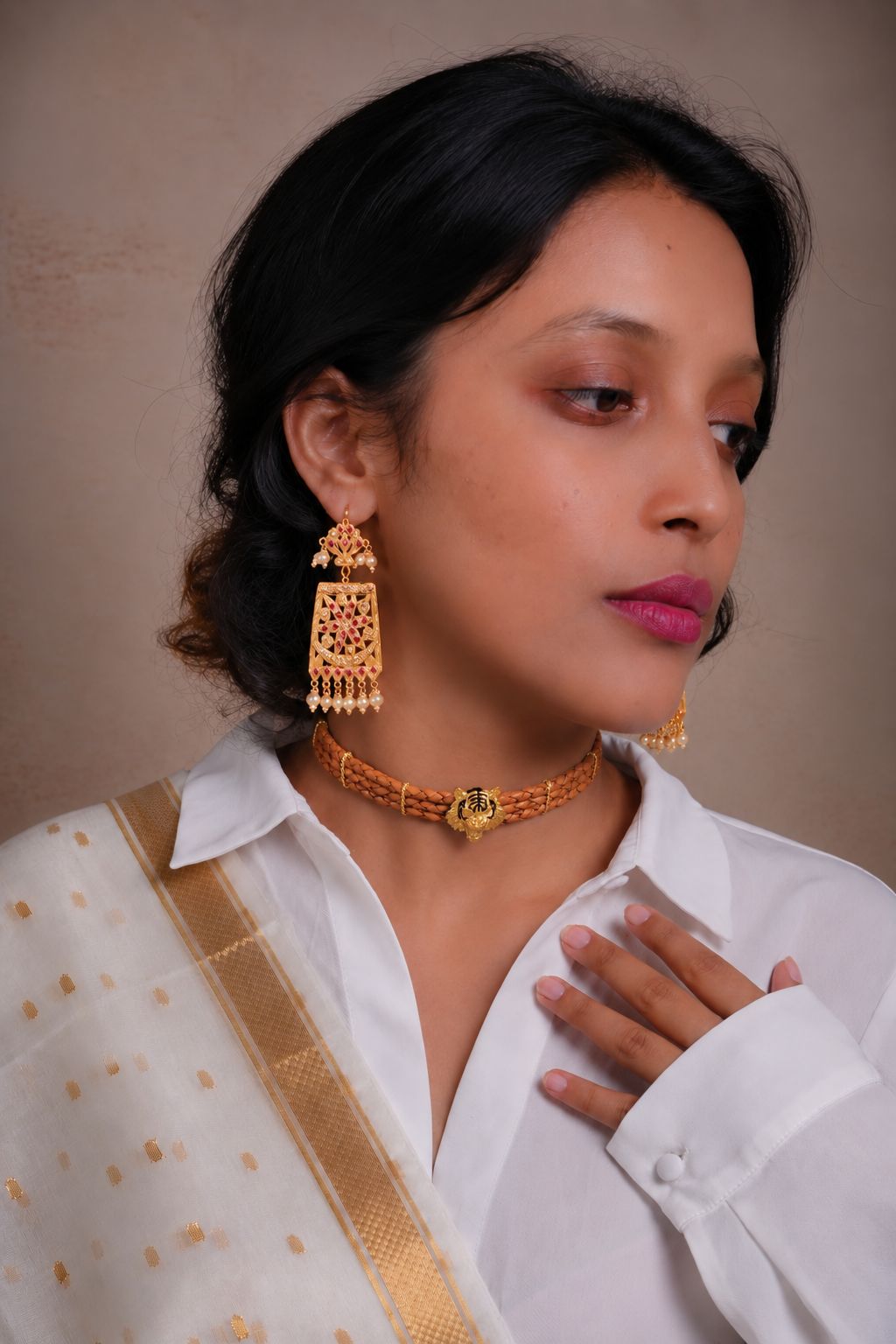 A Totapari model in a closed-collar white shirt wearing patra-style silver statement earrings and a leather choker with a gold-plated alloy tiger.